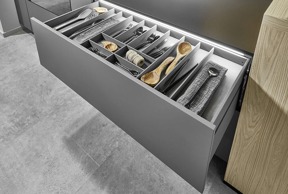 Frau greift nach Topf im Küchenschrank – ergonomische Küchenauszüge mit Vollauszug für Töpfe – KüchenMarkt