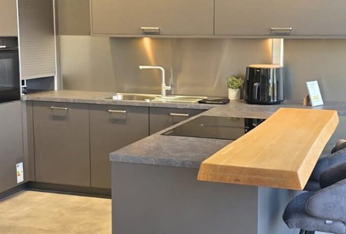 Moderne U-Küche mit Holztheke, dunklen Fronten und offenem Küchenbereich im KüchenMarkt Eching