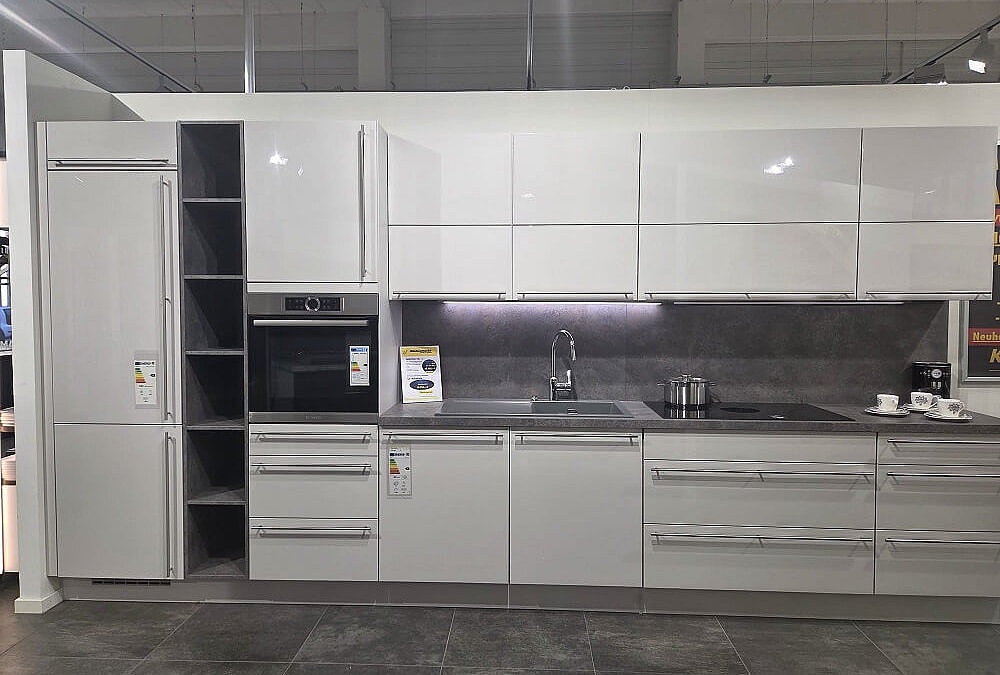 Gesamtansicht der modernen 435 cm Novalux Küchenzeile (Koje 22) in Seidengrau Hochglanz mit integriertem Kühlschrank und Backofen.