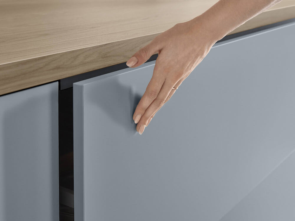 Hand öffnet grifflosen Unterschrank – modernes Push-to-Open-System mit Vollauszug – KüchenMarkt