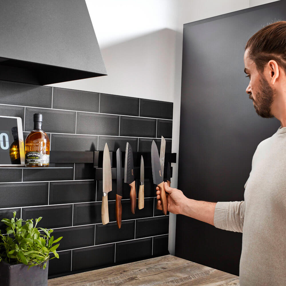 Messer sicher aufbewahren: Mann wählt Messer von Magnetleiste, sichere & griffbereite Aufbewahrung in der Küche.