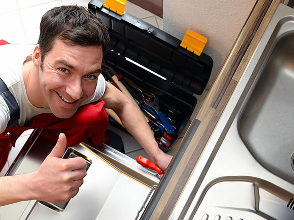 Monteur arbeitet mit Werkzeug an einer Küche neben der Spüle