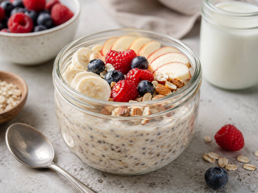 Glas mit Overnight Oats, Joghurt, Beeren und Haferflocken als vorbereitetes Frühstück