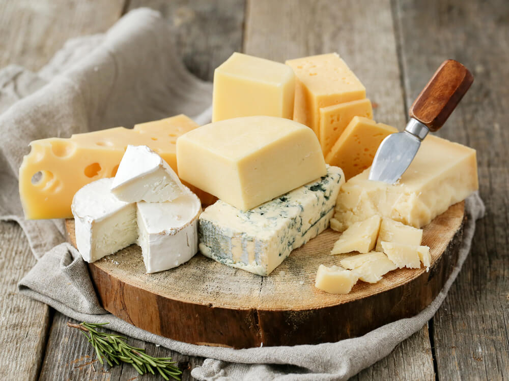 Verschiedene Käsesorten auf einem Holzbrett – Camembert, Blauschimmelkäse und Schnittkäse als Basis für den besten Käse zum Überbacken