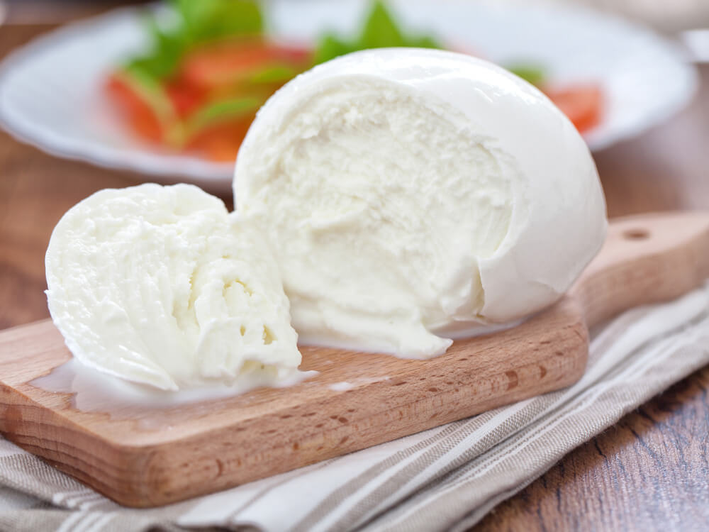 Frischer Mozzarella und Büffelmozzarella, angeschnitten auf einem Holzbrett – milder Käse zum Überbacken für Pizza und Aufläufe