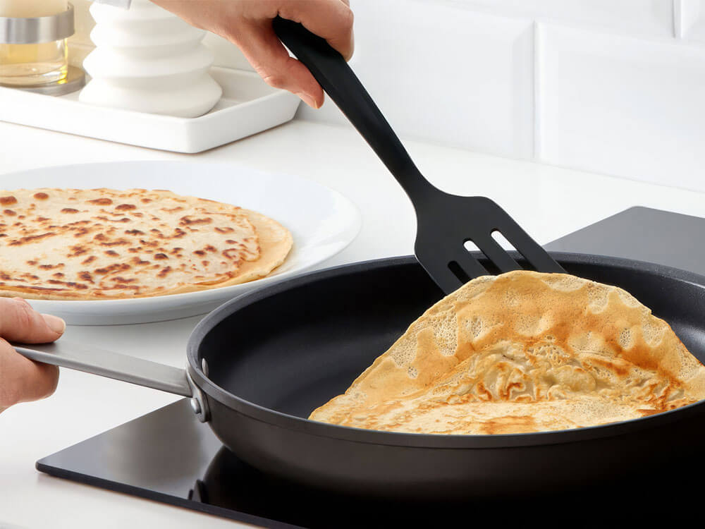Pfannkuchen in Antihaft-Pfanne mit Pfannenwender wenden