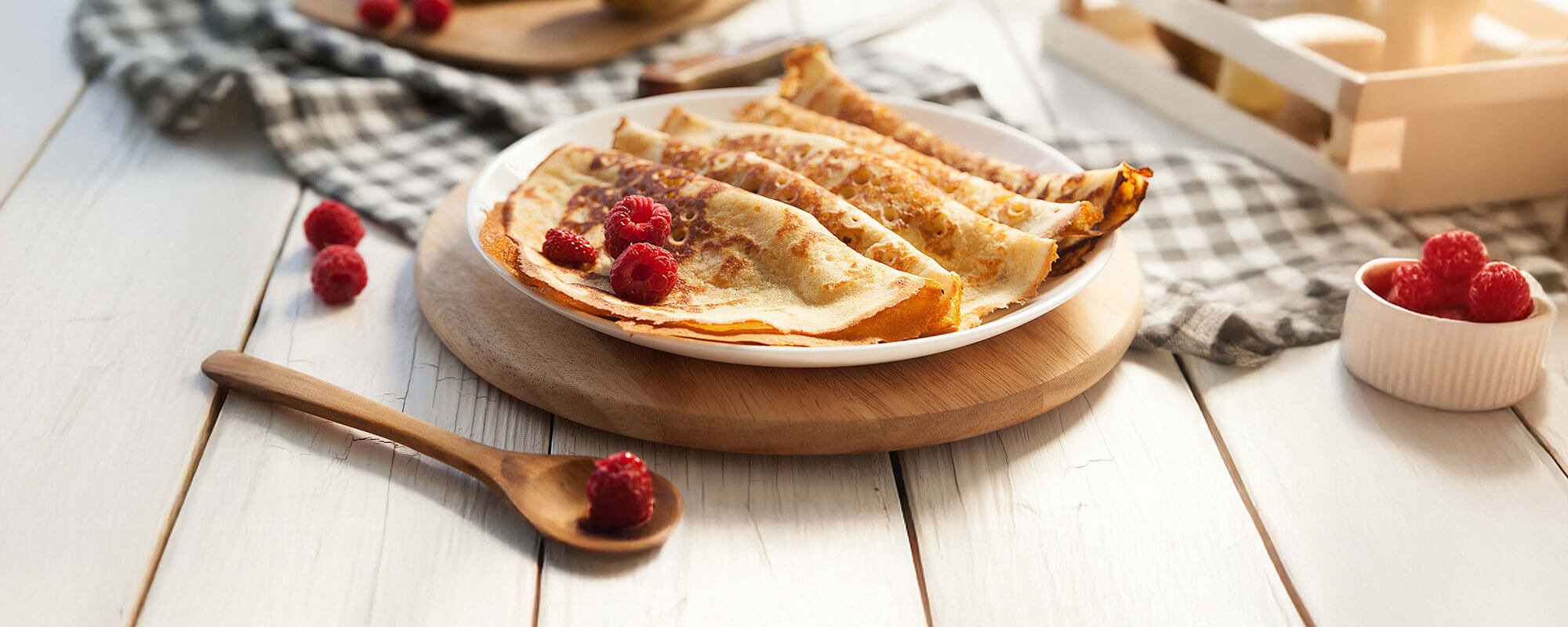 Fertige Pfannkuchen mit frischen Himbeeren auf Holztisch serviert
