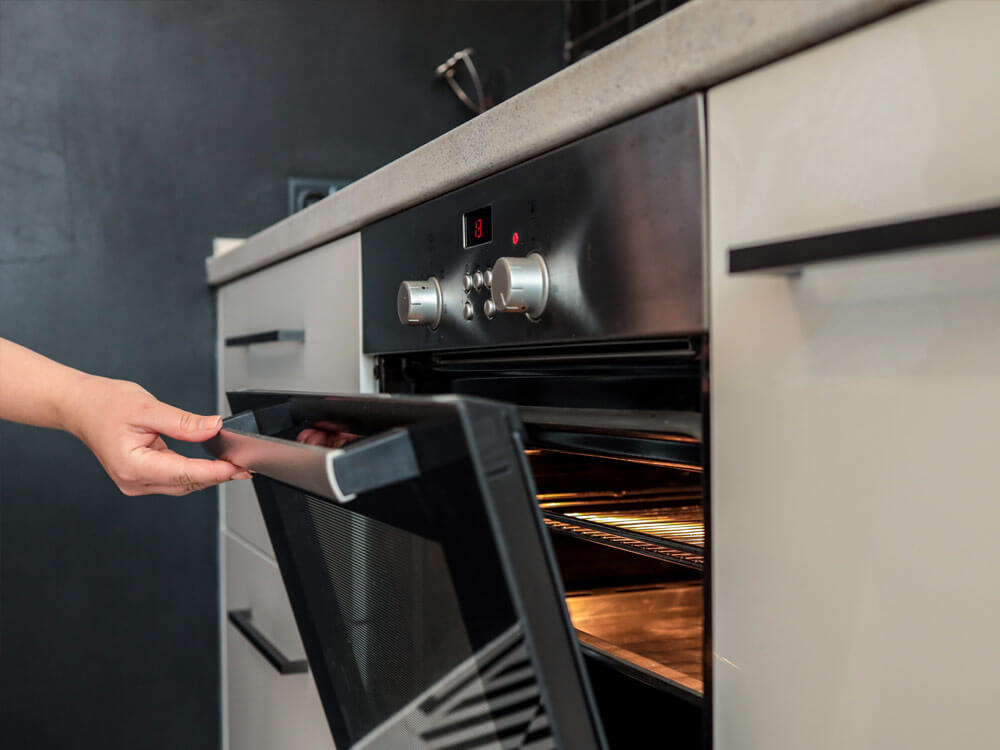 Frau öffnet Backofen und kontrolliert die Backzeit bei Umluft-, Ober-, Unterhitze-Einstellung