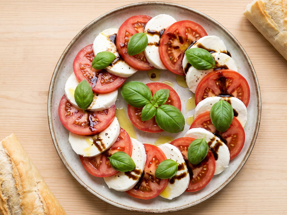 Caprese mit Tomaten, Mozzarella und frischen Basilikumblättern