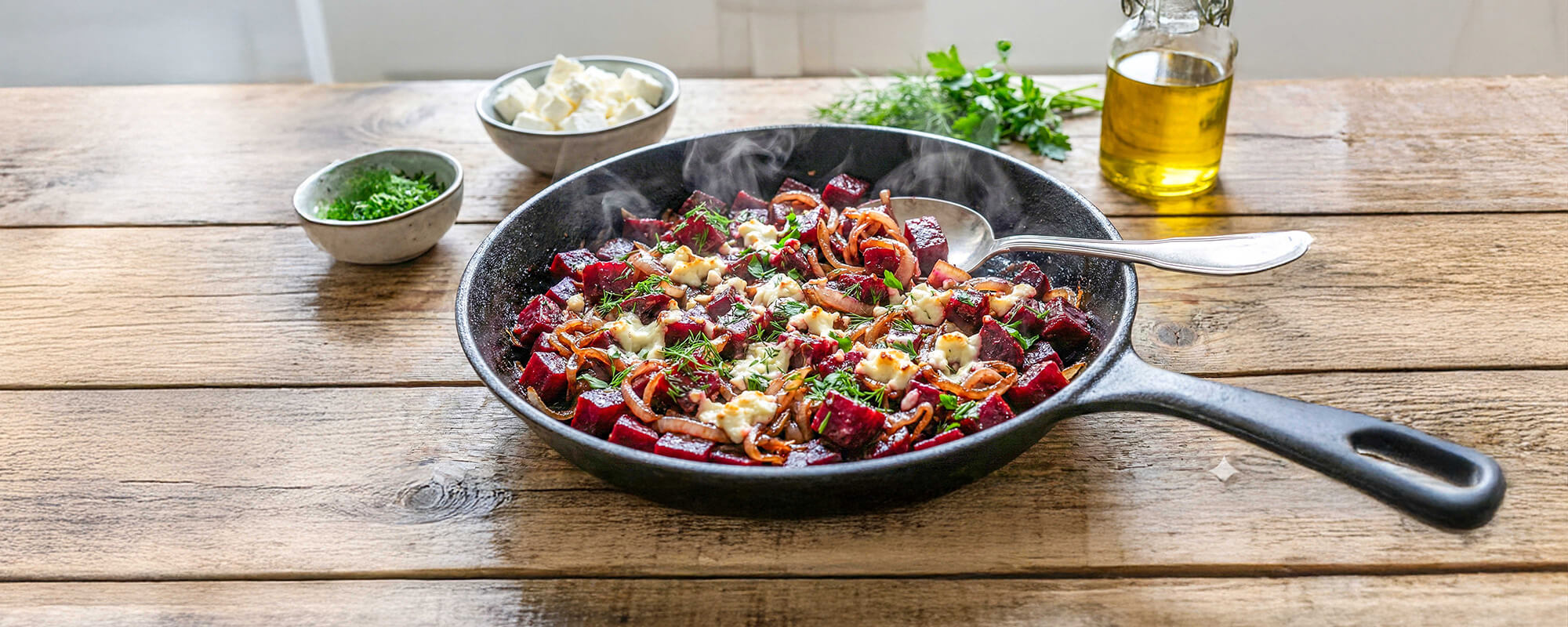 Zutaten für das Rote-Bete-Pfanne Rezept mit frischen Rote-Bete-Knollen, Zwiebeln, Knoblauch und Kräutern auf einem Holztisch.