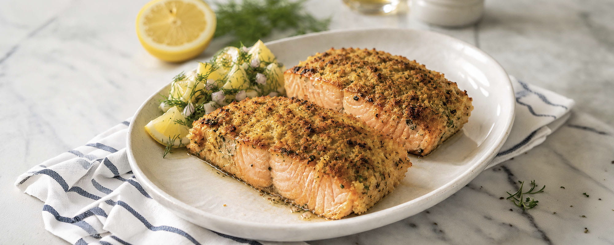 Lachsfilet mit Zitronen-Knusperkruste auf einem Teller mit Dill und Zitrone