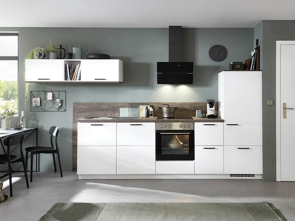 Kompakte Aktionsküche in Weiß ultramatt mit dunkler Holzrückwand, schwarzer Abzugshaube und griffloser Optik