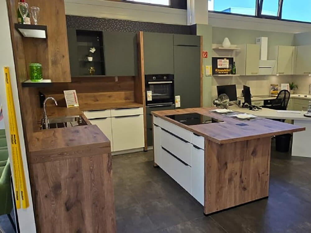 Moderne L-Küche mit Kochinsel, Holzoptik und dunklen Fronten in der KüchenMarkt Ausstellung Landshut-Nord