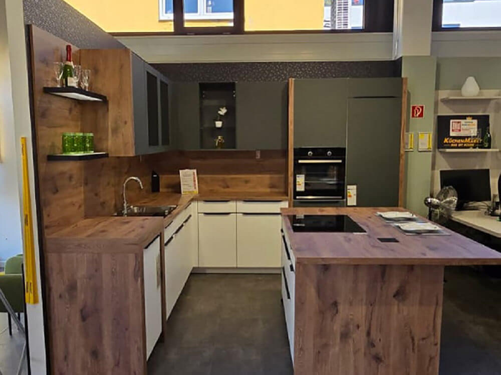 Moderne L-Küche mit Kochinsel, Holzoptik und angrenzendem Essbereich in Landshut-Nord
