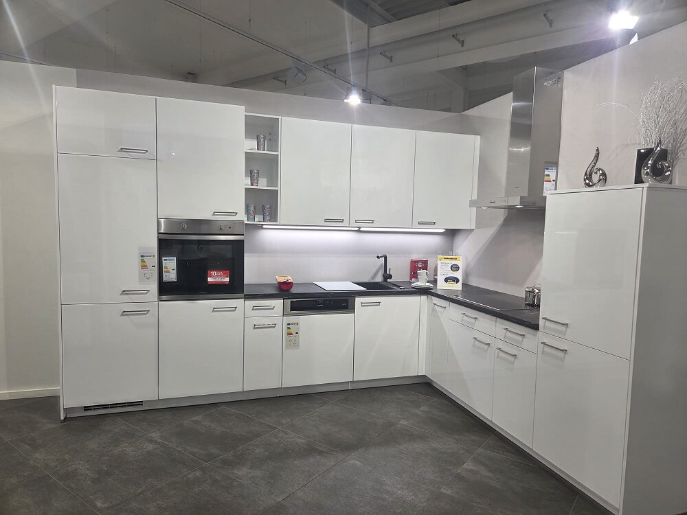 Gesamtansicht der U-Küche Touch (Koje 05) in Pastellblau Matt mit Holzarbeitsplatte, Kochfeld und hochgebautem Kühlschrank.