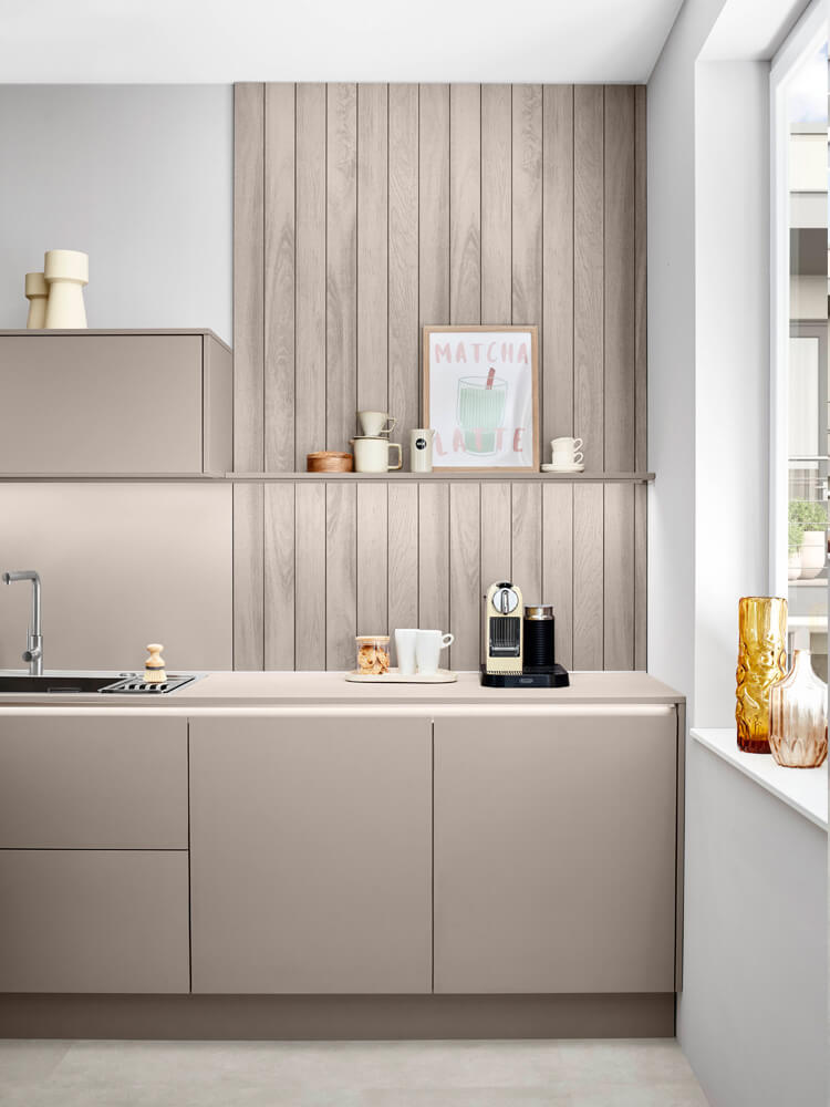 Spülenbereich der modernen Einbauküche mit moderner Armatur und Wandverkleidung in heller Holzoptik für natürliches Ambiente