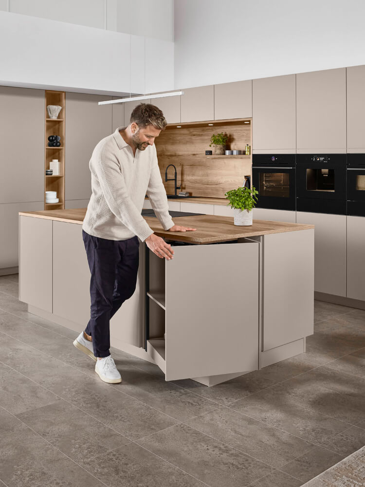 Person öffnet Auszüge der grifflosen Senso 483 Kücheninsel für komfortable Bedienung
