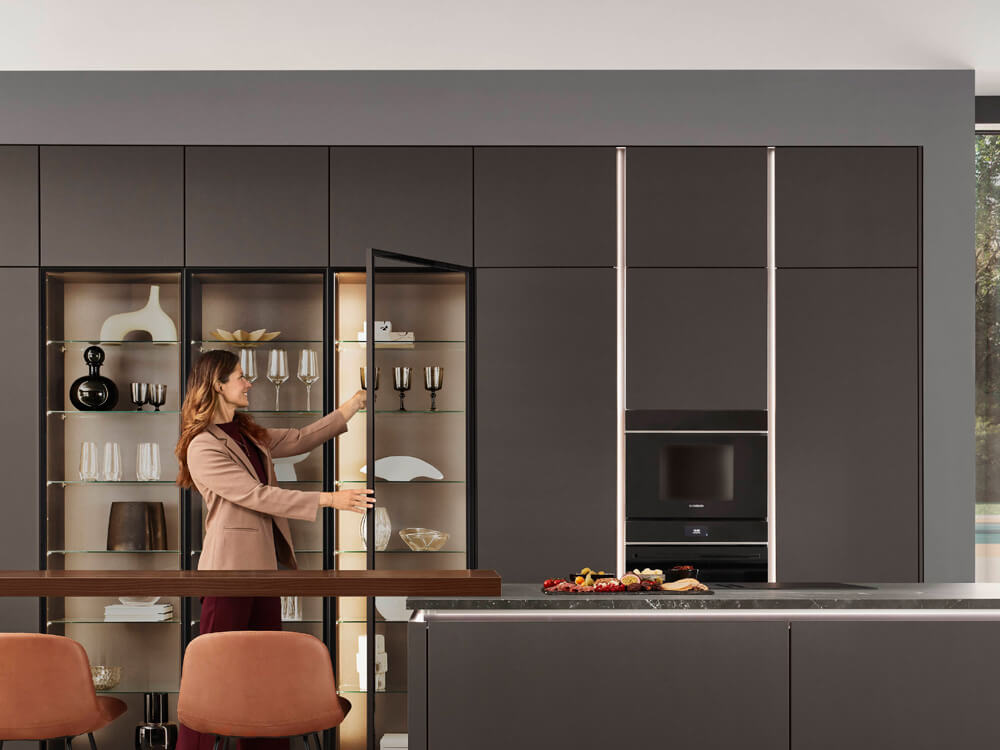 Person an der beleuchteten Vitrine der Softline 505 in moderner Wohnküche