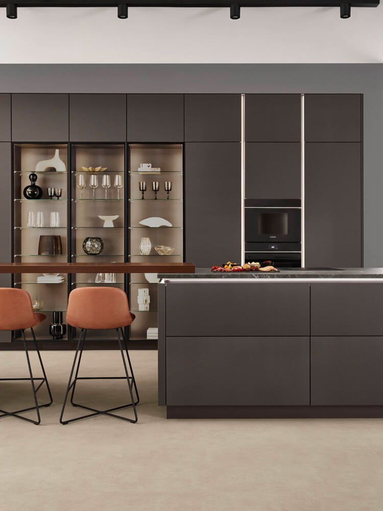 Detail der Kücheninsel mit Sitzplatz und beleuchteten Schaukästen in Coffee matt