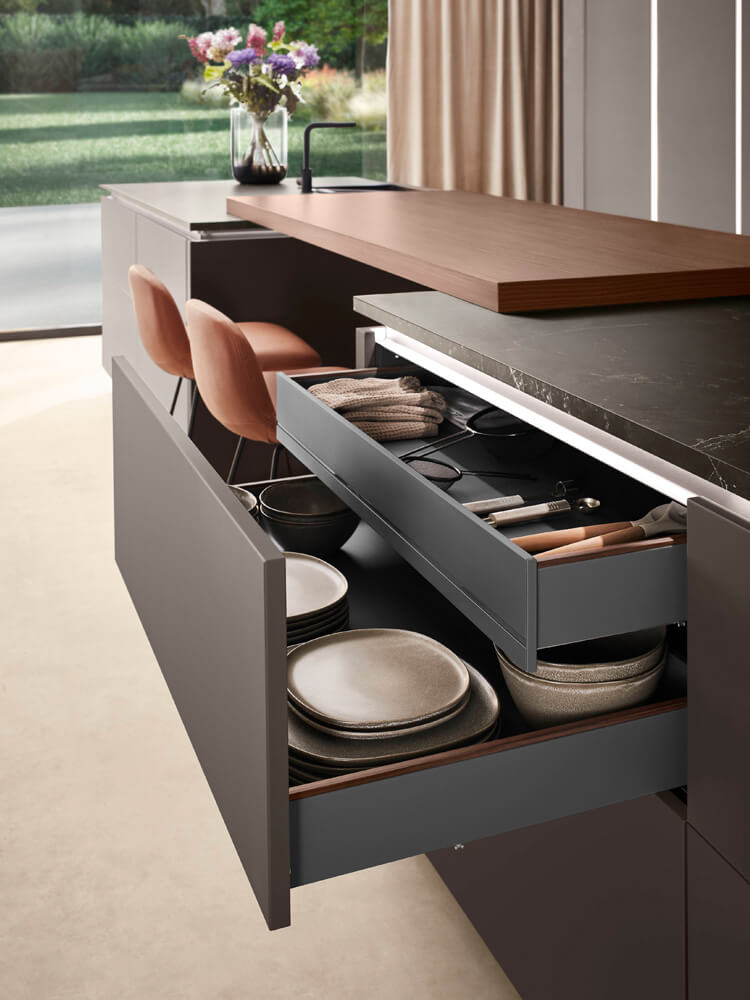 Geöffnete Auszüge unter der Kücheninsel mit Holztheke für viel Stauraum