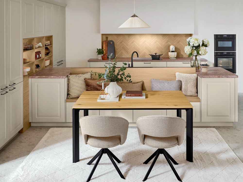 Moderne Landhausküche in Cremeweiß mit Sitzbank-Lösung und Holz-Küchenrückwand im Fischgrät-Design